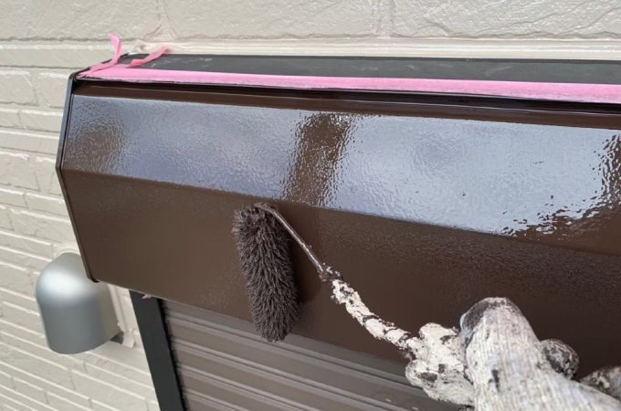 シャッターボックスの上塗り塗装作業中の様子 刷毛を使用して鉄部を丁寧に仕上げている施工写真