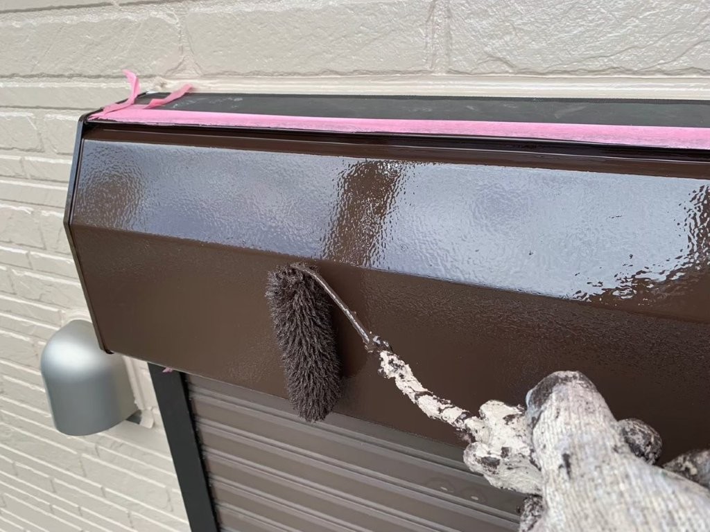 シャッターボックスの上塗り塗装作業中の様子 刷毛を使用して鉄部を丁寧に仕上げている施工写真