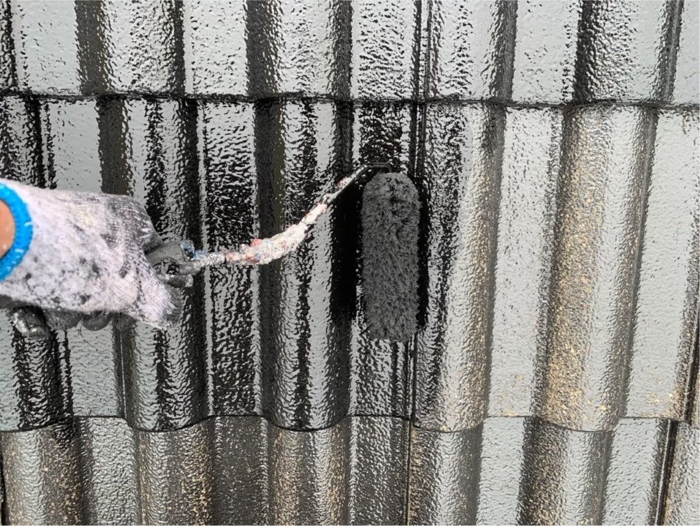 屋根瓦の中塗り塗装作業中 塗装範囲を広げながら均一に主材を塗布している施工写真