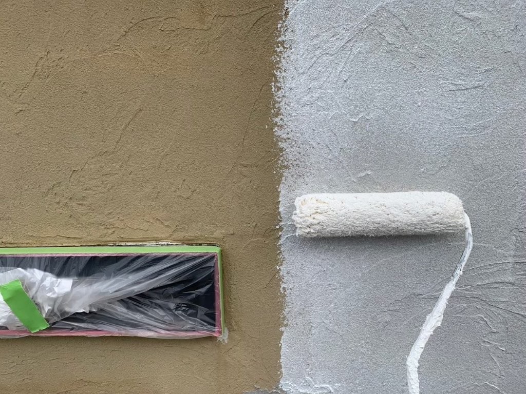 モルタル外壁の下塗り塗装中 フィラーをローラーで塗布し吸い込み止めと下地調整を行っている様子